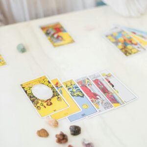 A detailed setup for tarot card reading, featuring various cards and crystals on a table.