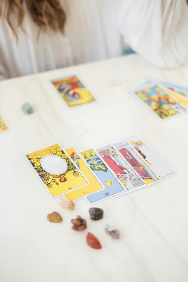 A detailed setup for tarot card reading, featuring various cards and crystals on a table.